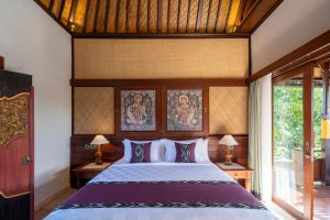 a bedroom with a large bed in a room at Puri Saraswati Dijiwa Ubud in Ubud