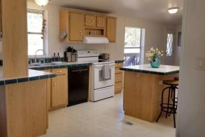 una cocina con armarios de madera y electrodomésticos blancos en Desert Hillside Lodge 25 mins from Sedona, en Cornville