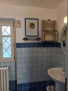 uma casa de banho com paredes em azulejos azuis e brancos e um lavatório. em Il giardino di Olivia em Guarene