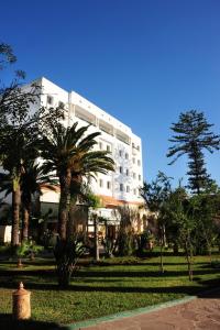 a white building with palm trees in front of it at Art suites in El Jadida
