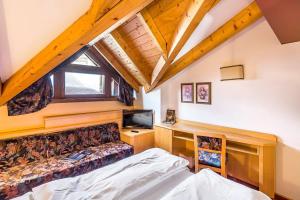 1 dormitorio con 1 cama y escritorio con TV en Hotel Cristiania, en Madonna di Campiglio