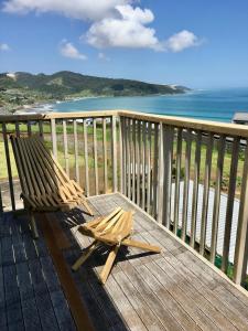 a wooden deck with a chair on top of the ocean at Panoramic Views - House in Ahipara