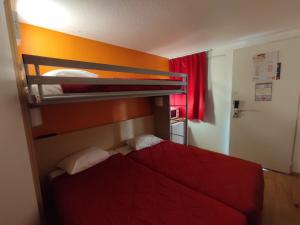 una camera con 2 letti a castello con lenzuola rosse di Première Classe Dijon Nord - Zénith a Digione