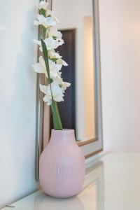 a pink vase with white flowers sitting on a table at Veluxa - Renovated! La Maison des Artist in Dubai