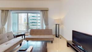a living room with a couch and a flat screen tv at Hometown Apartments - Waterfront 1 Bedroom apartment in Westside Marina in Dubai