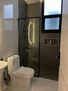 a bathroom with a toilet and a glass shower at Smart Entry Apartment in Riyadh