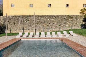 a pool with chairs and a building in the background at Rural Mas Hortus in Girona