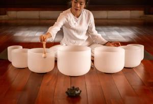 a woman sitting on the floor next to white bowls at Senna Wellness Retreat in Bắc Ninh