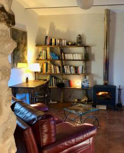 sala de estar con sofá de cuero y chimenea en Le moulin du Rubeguet, en Saint-Julien-de-Cassagnas