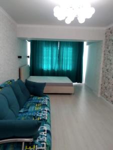 a living room with a couch and a bed at Молодежный in Almaty