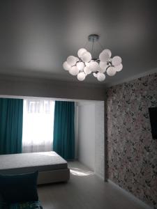 a bedroom with a bed and a chandelier at Молодежный in Almaty