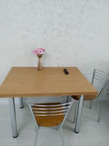 een houten tafel met een vaas met bloemen erop bij Молодежный in Alma-Ata