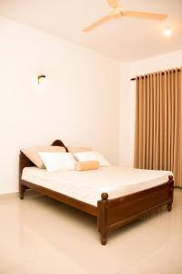 a bed in a bedroom with a ceiling fan at Mistry Apartments Weligama in Weligama
