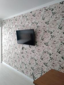 a tv on a wall with pink flowers at Молодежный in Almaty