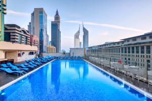 a large swimming pool with chairs and a city skyline at Gevora Hotel in Dubai
