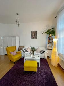 ein Wohnzimmer mit einem Sofa, einem Tisch und gelben Stühlen in der Unterkunft «Breakfast at Tiffany's» in Leipzig
