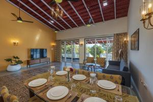a dining room with a table and a living room at SaffronStays Mariposa by the River Rio, Karjat in Karjat