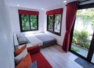 a bedroom with a bed and a couch and windows at Cửa Biển Homestay in Hai Phong
