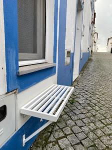 un banc blanc assis à l'extérieur d'un bâtiment bleu dans l'établissement Casa Olivença, à Arraiolos