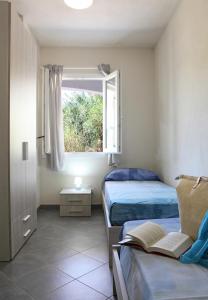 een slaapkamer met 2 bedden en een raam met een boek bij Casa Bianca Marea in Santa Maria Navarrese
