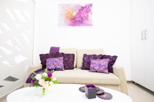 a living room with purple pillows and a couch at White home in Timişoara