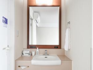 W łazience znajduje się umywalka i lustro. w obiekcie Vessel Hotel Kanda Kitakyushu Airport w mieście Kanda