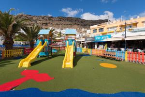 a playground with a slide in a market with palm trees at Mogan Beach Blue Sky in Mogán