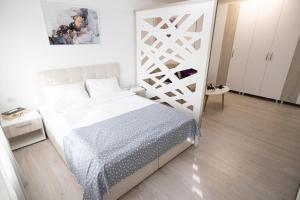 um quarto com uma cama branca e piso em madeira em White home em Timisoara