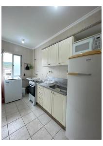 Una cocina con gabinetes blancos y un refrigerador blanco. en AP com Piscina em Porto Belo, en Porto Belo