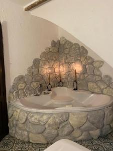 une baignoire dans un mur en pierre avec des bougies dans l'établissement El Escondite de Martina, Áticos Románticos, à Setenil de las Bodegas
