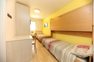 Una fila de camas en una habitación con paredes amarillas. en Villa Marta, en Mazzin