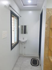 a white bathroom with a sink and a window at Hotel Taj Bi Plaza in Aurangabad