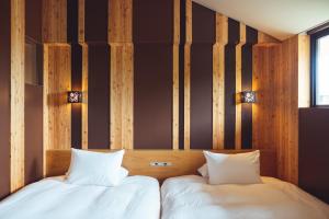 Duas camas num quarto com paredes de madeira em SETRE Naramachi セトレ ならまち em Nara