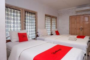 two beds in a room with red and white pillows at RedDoorz Syariah near Plengkung Gading 2 in Yogyakarta