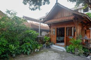 uma pequena casa de madeira com um alpendre com plantas em RedDoorz Syariah near Plengkung Gading 2 em Yogyakarta