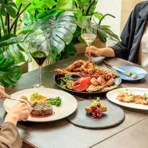 - une table avec des assiettes de nourriture et des verres de vin dans l'établissement Resorts World Sentosa - Crockfords Tower, à Singapour