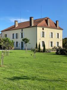 un gran edificio con un campo de césped delante de él en Large House near Marciac & Heated Salt Water Pool, en Plaisance