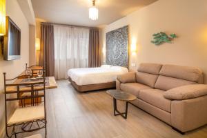 un soggiorno con divano e letto di Apartamentos Sevilla Este by QHotels a Siviglia
