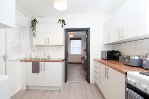 una cocina con armarios blancos y fregadero en LARGE GROUPS- 5 bed House in Harringay, en Londres