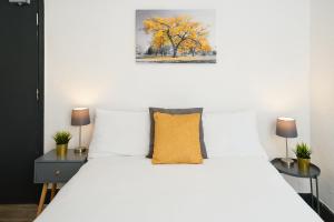 sypialnia z białym łóżkiem i żółtą poduszką w obiekcie LARGE GROUPS- 5 bed House in Harringay w Londynie
