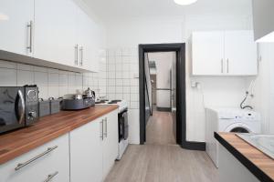 cocina con armarios blancos, lavadora y secadora en LARGE GROUPS- 5 bed House in Harringay, en Londres