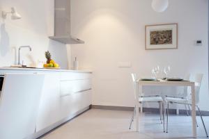 een keuken met witte kasten en een tafel en stoelen bij Casas de Sevilla - Apartamento A Pie de Muralla - Centro Histórico in Sevilla