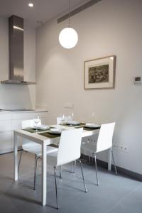een eetkamer met een tafel en witte stoelen bij Casas de Sevilla - Apartamento A Pie de Muralla - Centro Histórico in Sevilla