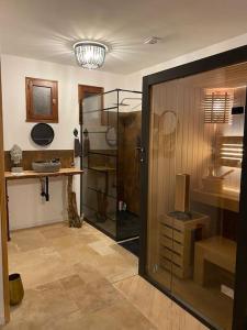 una habitación con una puerta de cristal y una habitación con un estante en Gîte privé avec sauna et balnéo en Brens