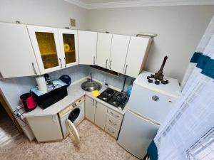 Elle comprend une petite cuisine avec des placards blancs et un réfrigérateur. dans l'établissement Апартаменты Ермекова 23, à Karaganda