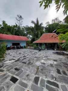 une cour en pierre en face d'un bâtiment avec un toit rouge dans l'établissement Villa Kamar Tamu Selomartani 2, à Sleman