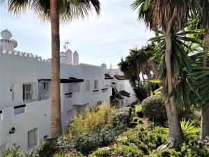 un edificio blanco con palmeras y plantas en Playa Lucera - ground floor apartment with sea views CS126, en Sitio de Calahonda