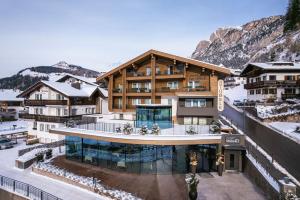 an image of a building with mountains in the background at Hotel Sun Valley in Selva di Val Gardena