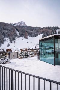 szklany budynek z widokiem na góry w obiekcie Hotel Sun Valley w mieście Selva di Val Gardena