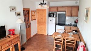 a kitchen with a table and chairs and a refrigerator at Appt T2 Cabine 4-6 personnes au pied des pistes in Orcières